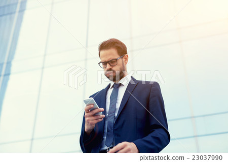 Confident manager reading news via cell telephone  23037990