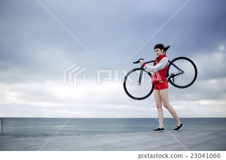 Girl standing on concrete pier seashore with bike Girl standing on concrete pier seashore with bike 23041066