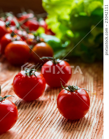Small cherry tomatoes on the wooden background Small cherry tomatoes on the wooden background 23042111