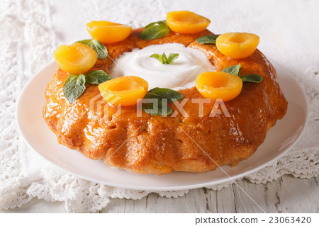 Tasty cake Savarin with apricots and mint close-up 23063420