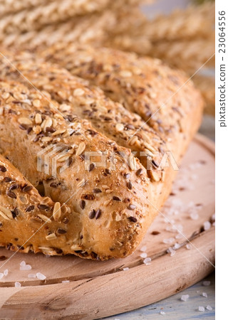Loaf of multicereal bread on wooden board 23064556