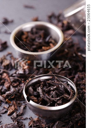 Strainer and metal bowl full of dry tea leaves 23064635