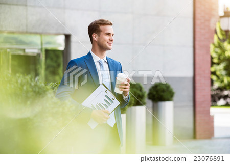 Handsome man standing near office building Handsome man standing near office building 23076891