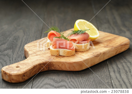 baguette slices with curred salmon and dill on wood table baguette slices with curred salmon and dill on wood table 23078838