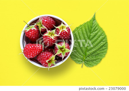 Raspberry and green leaf on yellow table 23079000