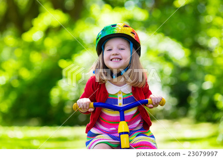 Little girl riding a tricycle 23079997