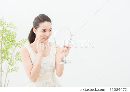 A woman looking at a mirror (Beauty 20's) 23084472