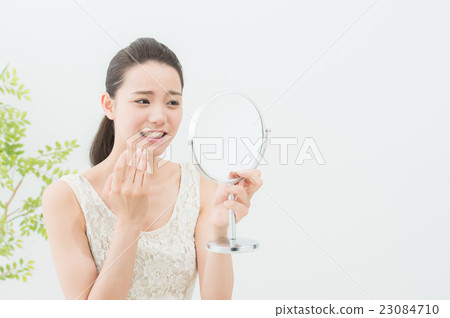 A woman looking at a mirror (dental care) 23084710