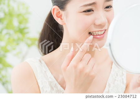 A woman looking at a mirror (dental care) 23084712