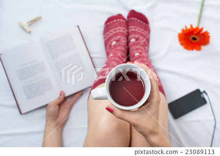 Woman reading a book and having cup of tea Woman reading a book and having cup of tea 23089113