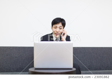 A businessman using a personal computer and a smartphone A businessman using a personal computer and a smartphone 23091862
