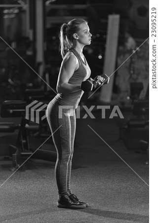 Young woman lifting the dumbbells Young woman lifting the dumbbells 23095219