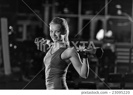 Young woman lifting the dumbbells Young woman lifting the dumbbells 23095220