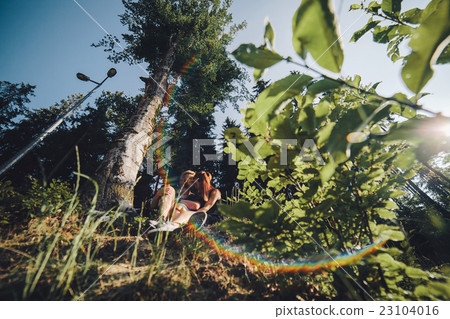 beautiful couple sitting in a forest near the tree 23104016