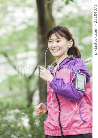 一個女人在智能手機上聽音樂時慢跑 23104073