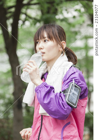 一個女人在智能手機上聽音樂時慢跑 23104077