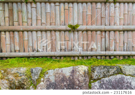 Bamboo fence on stone with green leaves . Bamboo fence on stone with green leaves . 23117616