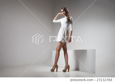 Girl in white dress posing against of grey Girl in white dress posing against of grey 23132368