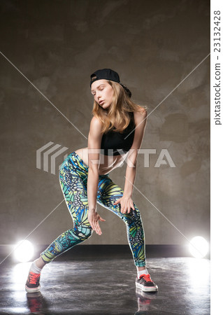 Dancer posing against of brown wall and lights 23132428