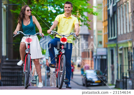 Young happy caucasian couple on bikes in Amsterdam Young happy caucasian couple on bikes in Amsterdam 23154634
