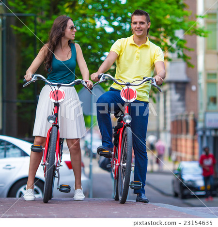 Young happy caucasian couple on bikes in Amsterdam Young happy caucasian couple on bikes in Amsterdam 23154635