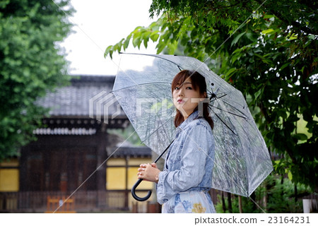 一個女人給一把傘婦女在雨季日本出現在寺廟裡 一個女人給一把傘婦女在雨季日本出現在寺廟裡 23164231