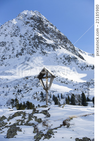 Cross in snowy mountain landscape Cross in snowy mountain landscape 23185980