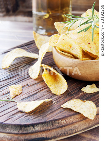 Chips in a wooden bowl and beer 23192259