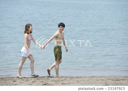 A couple walking along the beach 23197923
