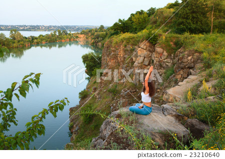 Young woman is practicing yoga near river 23210640