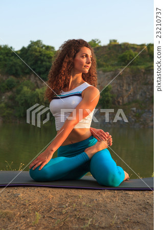 Young woman is practicing yoga near river Young woman is practicing yoga near river 23210737