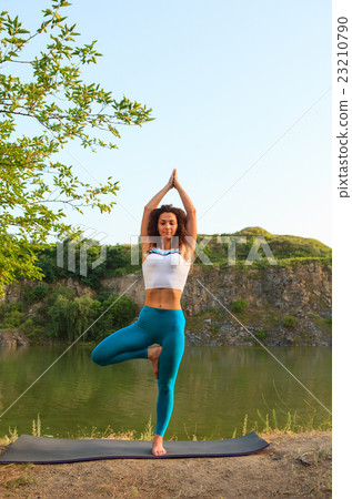Young woman is practicing yoga near river 23210790