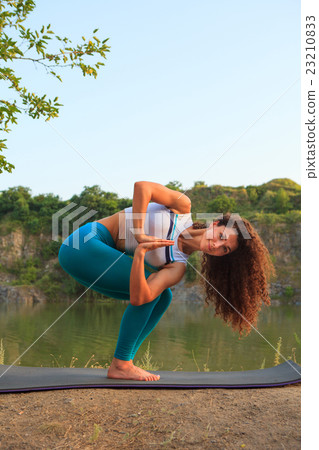 Young woman is practicing yoga near river 23210833
