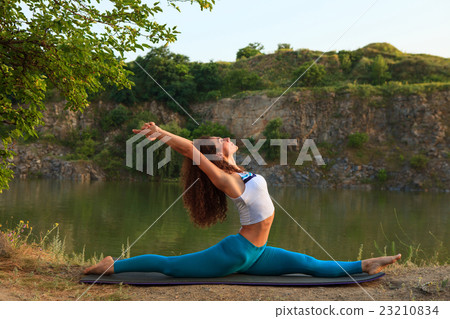 Young woman is practicing yoga near river 23210834