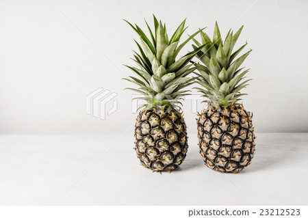 Pineapples on wooden table over white background Pineapples on wooden table over white background 23212523