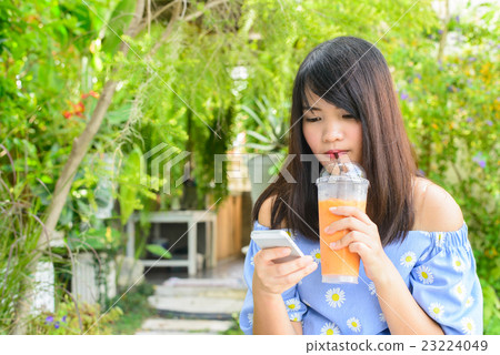 Woman typing text message on smart phone in a cafe Woman typing text message on smart phone in a cafe 23224049