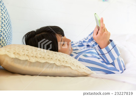 一名婦女在床上的看一個智能手機 一名婦女在床上的看一個智能手機 23227819