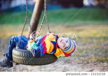 Little kid boy swinging on playground outdoors Little kid boy swinging on playground outdoors 23232536