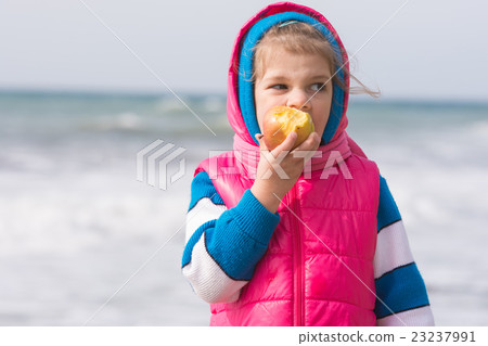 Five-year girl eating an apple on the background of the sea coast Five-year girl eating an apple on the background of the sea coast 23237991