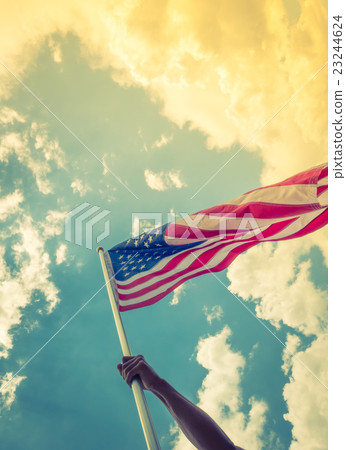 American flag with stars and stripes hold with hands against blue sky ( Filtered image processed vintage effect ) American flag with stars and stripes hold with hands against blue sky ( Filtered image processed vintage effect ) 23244624