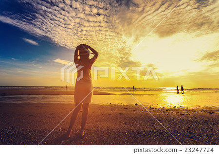young woman standing on sand and looking to a sky 23247724