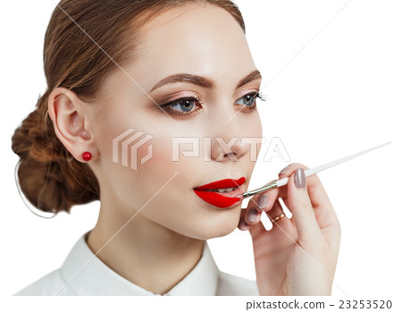 Young woman applying lipstick with an applicator 23253520