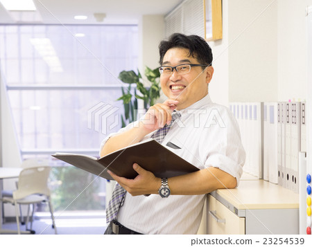 A businessman laughing with a file in hand A businessman laughing with a file in hand 23254539