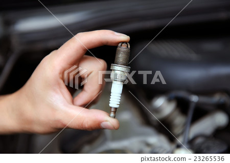 Auto mechanic holds an spark plug 23265536