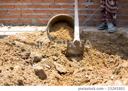 Construction workers putting sand in the bucket  23265801