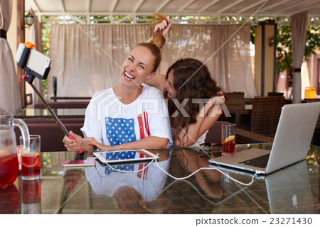 Two girls taking picture with cell telephone  23271430