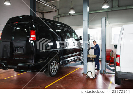 Mechanic rising car on lift before maintenance Mechanic rising car on lift before maintenance 23272144