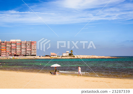 Sunny Mediterranean beach, Tourists relax on sand Sunny Mediterranean beach, Tourists relax on sand 23287339