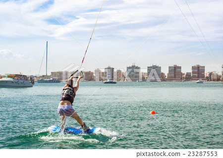Cute girl learns to surf on background of yachts 23287553