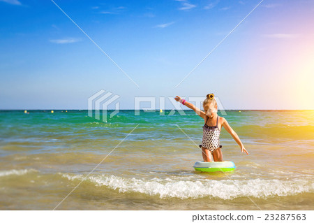 Cute girl in swimsuit bathes on waves in sea Cute girl in swimsuit bathes on waves in sea 23287563